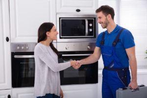 Appliance service technician shaking hands with a local customer following a service visit