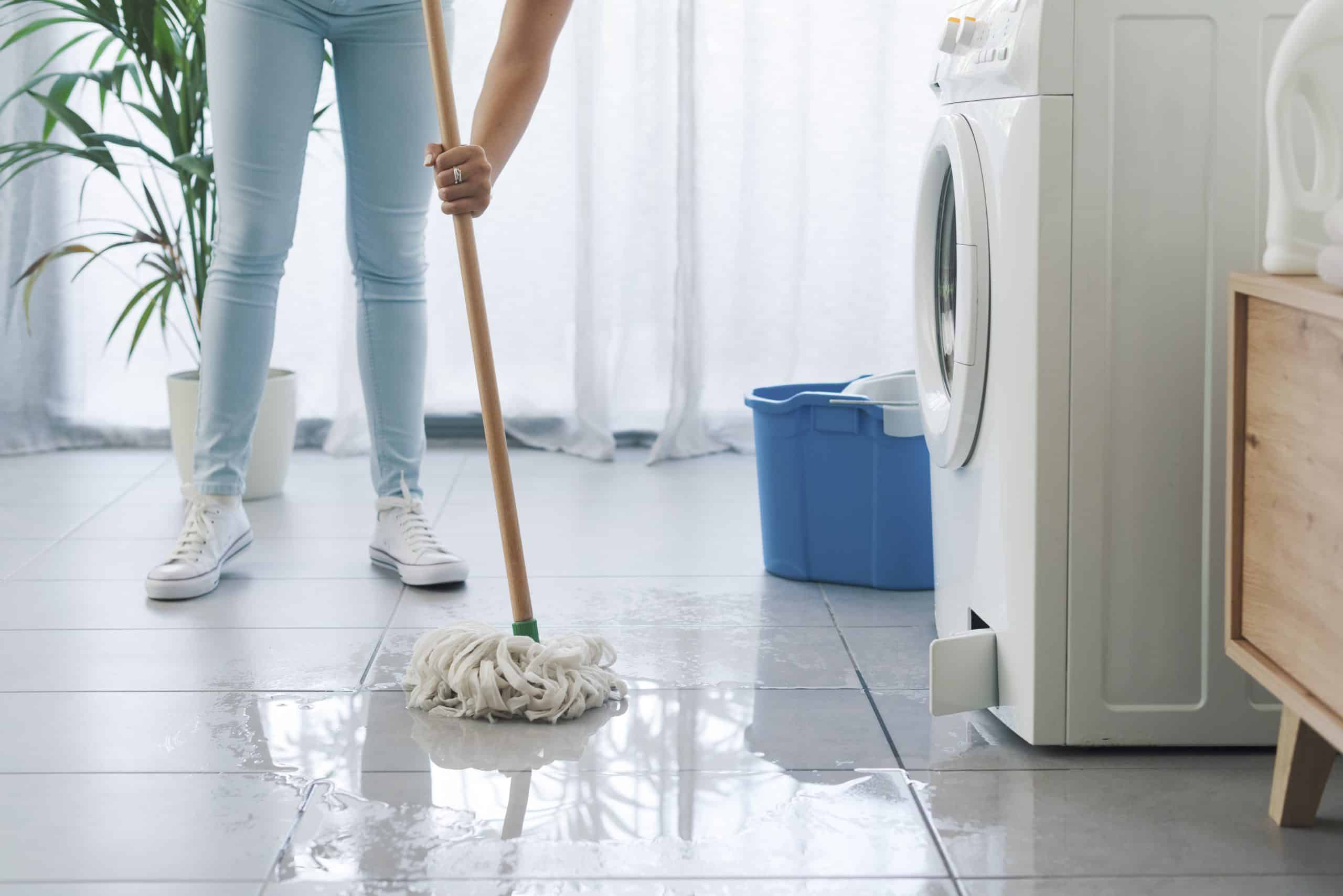 Woman cleaning with a mop her washing machine flood
