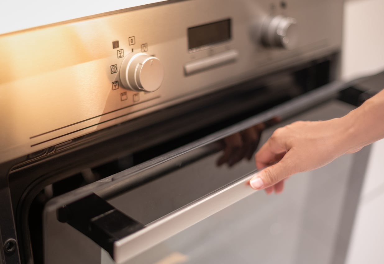 A Woman's Hand Reaching For The Oven Rail.